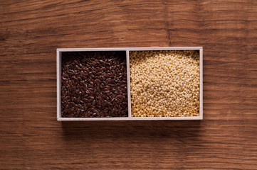 linseed and millet in wooden box on brown wooden table - top vie