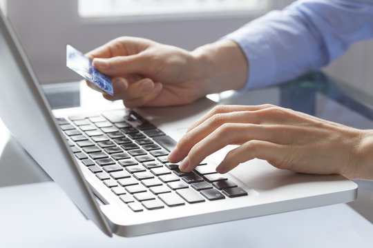 Hands holding credit card and typing on laptop, online payment
