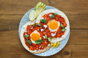 Mexican breakfast huevos rancheros: fried egg with salsa closeup in the pan