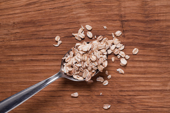 oat flakes on metal spoon on brown wooden table