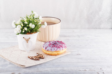 Three donut, a cup of coffee and willow on a white table