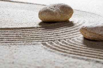 Fototapeta na wymiar zen sand still-life - textured pebbles set across sinuous waves for concept of spirituality or beauty with inner peace