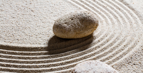 Fototapeta na wymiar zen sand still-life - textured stones set on sinuous waves for concept of flexibility or suppleness with inner peace