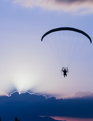 Silhouette paramotor / paraglider flying on sky.