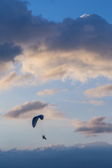 Silhouette paramotor / paraglider flying on sky.