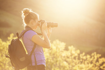 Woman taking photos outdoors on a sunny evening with a digital SLR camera