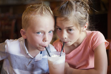 Cute kids sharing a mint Italian soda drink at a cafe