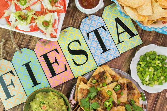 Mexican fiesta table with nachos, tortilla chips, quesadillas, guacamole dip.