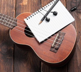 Ukulele guitar notebook and pencil on wood