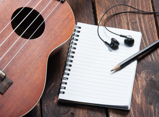 Ukulele guitar notebook and pencil on wood