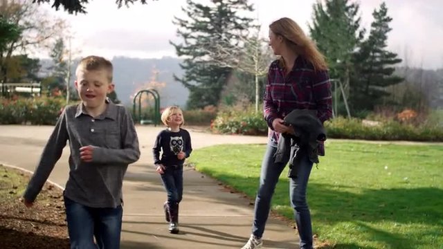 A family walking together on a path in a park on a sunny day, slow motion