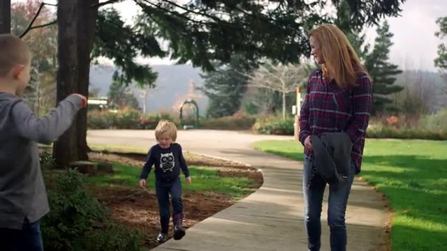A family walking together on a path in a park on a sunny day, slow motion