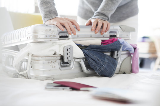 Women are packed a lot of clothes in the suitcase