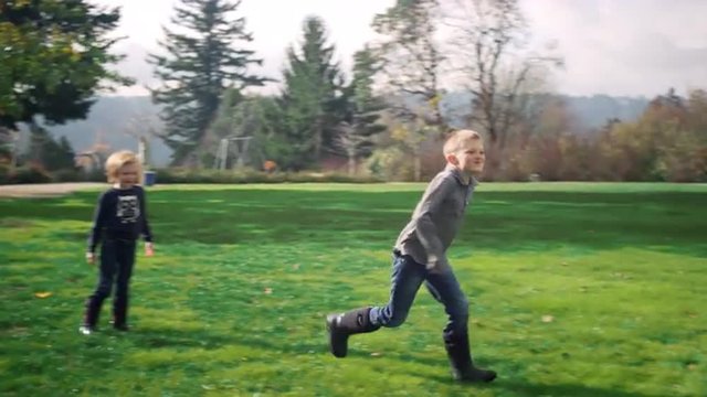 Siblings fighting and then running down a path at a park, in slow motion