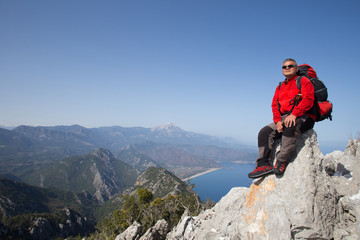Hiker standing on top of the mountain with valley on the background.