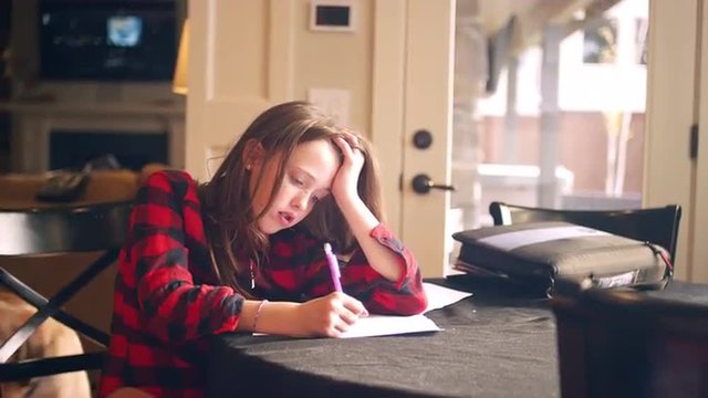 Young teen doing homework at the kitchen table and asking for help