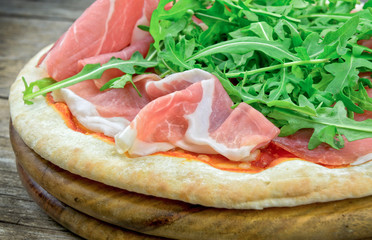 Italian pizza with ham and fresh rocket salad