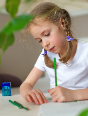 Little girl drawing with pencil at home.