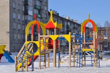 Fototapeta na wymiar Children playground. Editorial image. Bright's design for children in the yard of a house. For the playground can see two houses and cars. Novokuznetsk, Kemerovo region, Russia. 03/07/2016