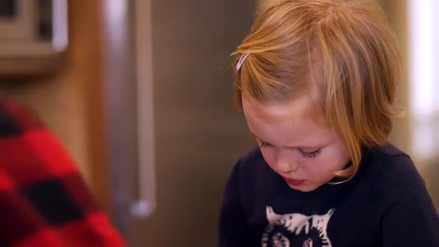 A little girl in a kitchen smells ingredients while cooking, slow motion