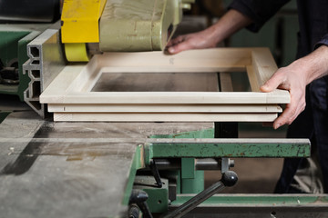 Carpenter's hands cutting wooden window frame - 104807320
