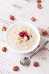Oatmeal with milk, nuts and strawberry jam and milk jug