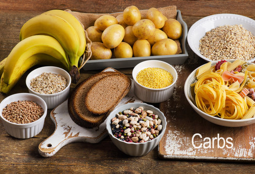 Foods high in carbohydrate on a rustic wooden background.