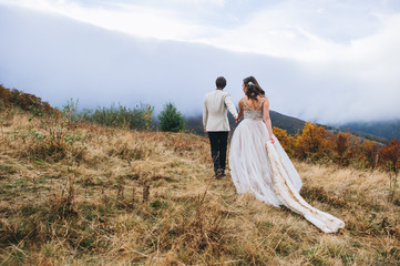 happy newly married couple posing in the mountains