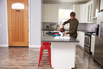 Young Man Making Hot Drink In Apartment Kitchen