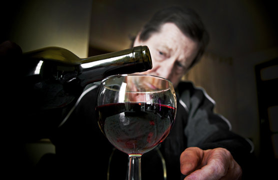 Bicchiere di vino rosso, sullo sfondo uomo anziano