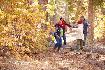 Grandparents With Children Walking Through Fall Woodland