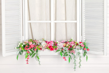 Fototapeta na wymiar Blooming flower bed under the window. Windowsill with flowers