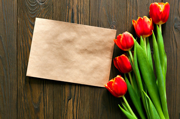 red tulips and kraft envelope on a wooden background
