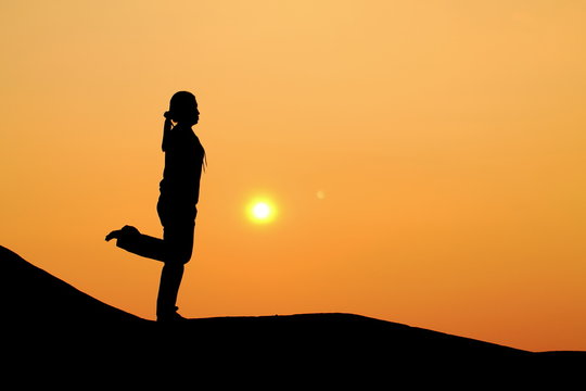 Silhouette picture of a woman plays yoga on the hill