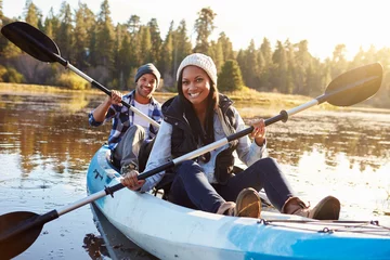 Foto op Canvas African American Couple Rowing Kayak On Lake © Monkey Business