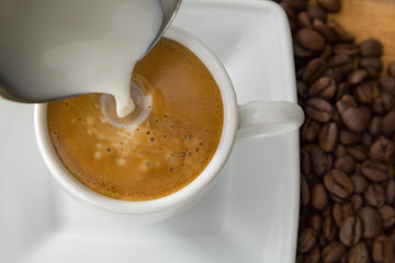 caffee in white cup with pouring milk