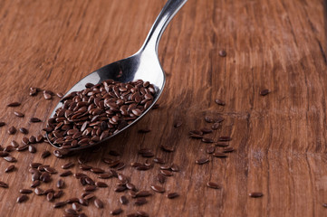 linseed on metal spoon on brown wooden table