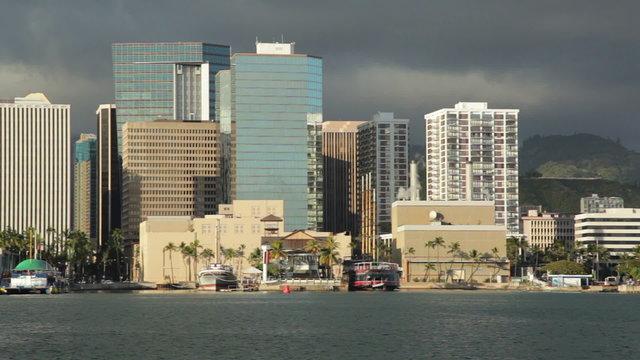 Panning left (northwest) view of downtown Honolulu high rises just before sunset, within Honolulu Harbor. The pan ends with the prominent landmark Aloha Tower in view.