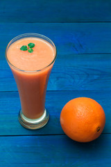 glass of fruit smoothie and orange
