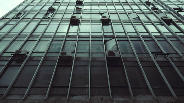 Passing by old abandoned urban building scyscraper offices tracking shot.Gimbal stabilized