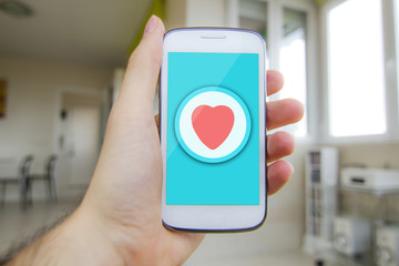 Man holding smartphone with heart button on the screen. All screen graphics are made up.