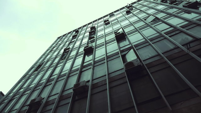 Passing by old abandoned urban building scyscraper offices tracking shot.Gimbal stabilized