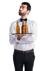 Waiter with beer bottles on the tray having doubts