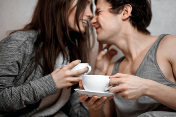 Young beautiful pair of lovers drink tea (coffee) in bed