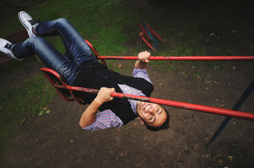 Young man having fun on swing on the playground