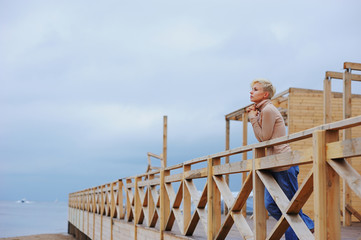 Young caucasian woman standing in a pavilion on the sea shore leaning over railing