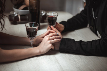 Beautiful young couple with glasses of red wine in luxury restaurant