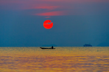 Fisherman in a boat in the sea at sunset background
