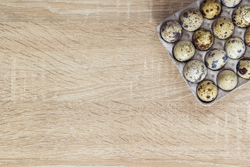 Quail eggs in the tray on a wooden background and empty space fo