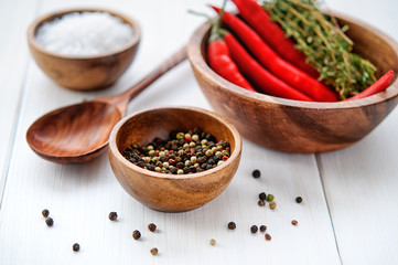 Salt, pepper, chili and thyme in bowls on white rustic wooden table